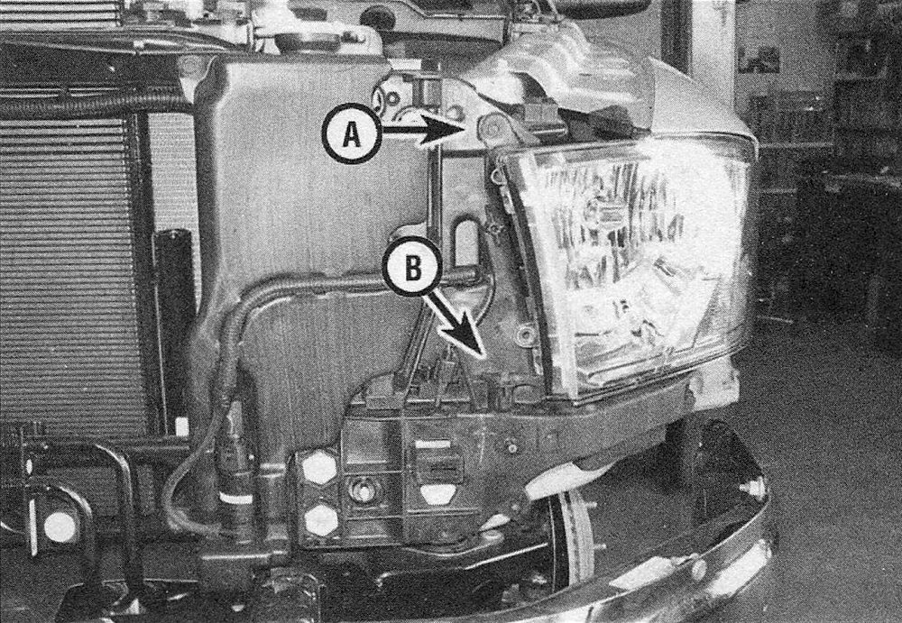 Ram Trucks Headlight housing - Remove the radiator top cover for access to the upper screw (A), then use a magnetic socket with a long extension to remove the vertical screw (B) - other components removed here for clarity