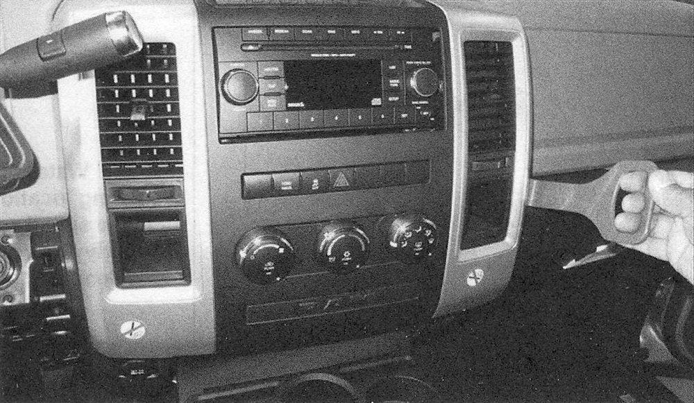 RAM Trucks Pull the center instrument panel out, then depress the tabs and detach the electrical connectors from the back of the heater/air conditioning control assembly